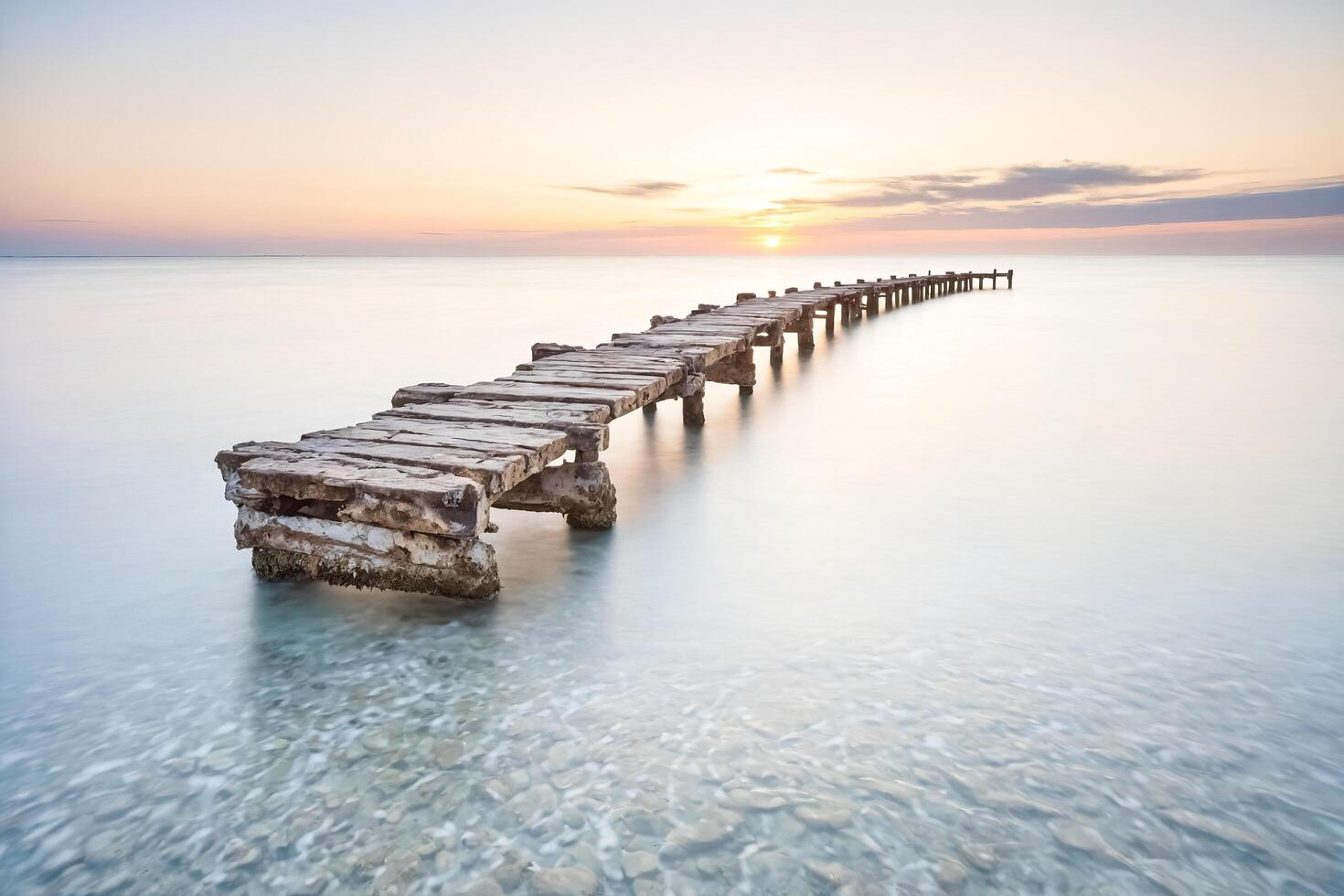 Wooden Pier Extending Into the Ocean at Sunset photo