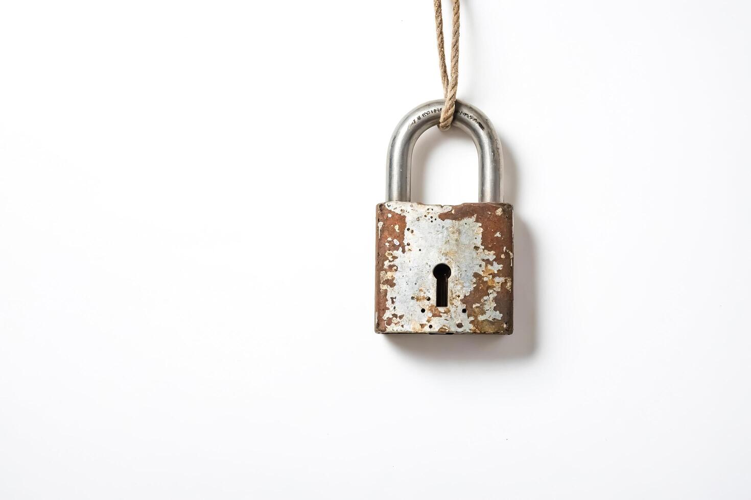 Rusty Padlock Hanging from Rope on White Background photo