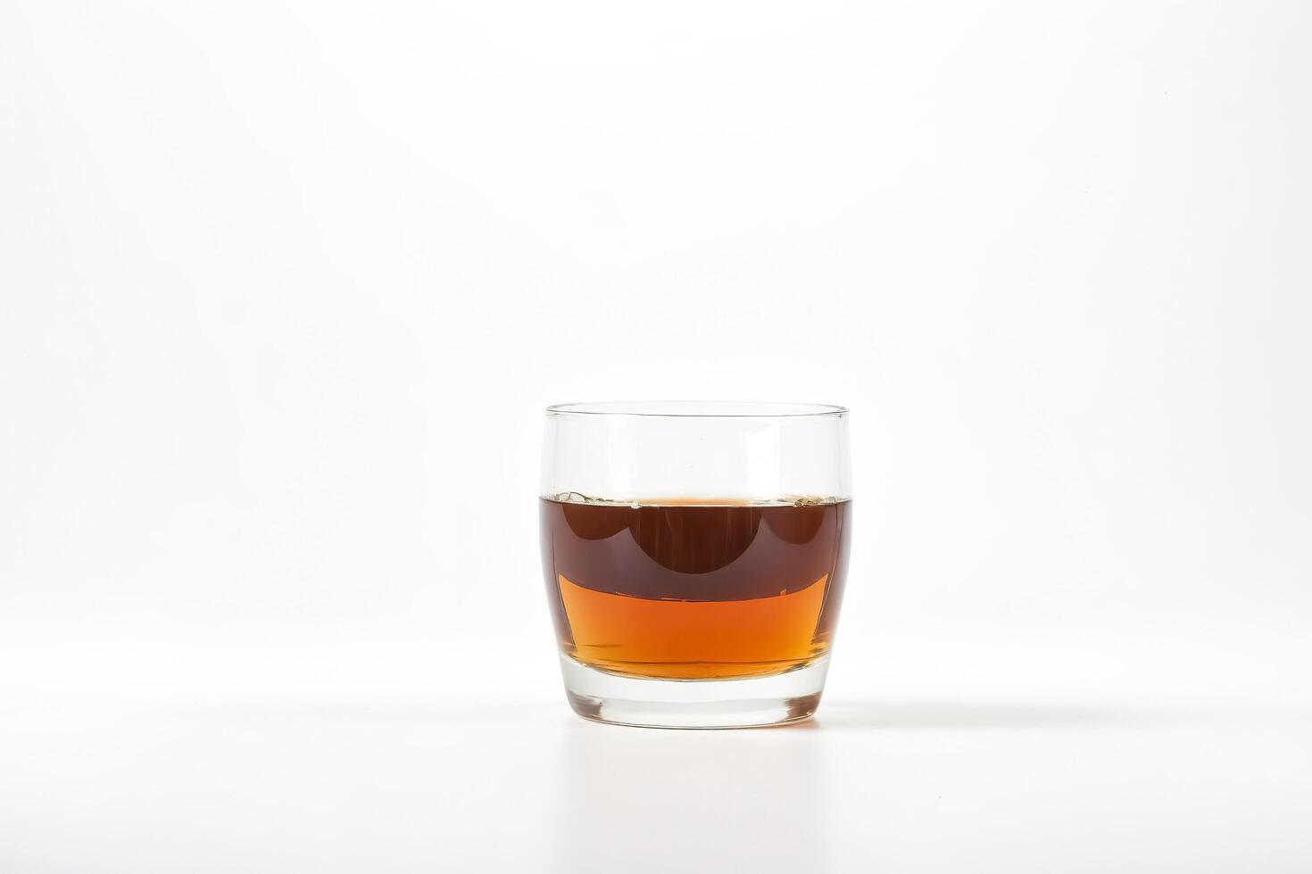 Glass of amber liquid on a white background photo