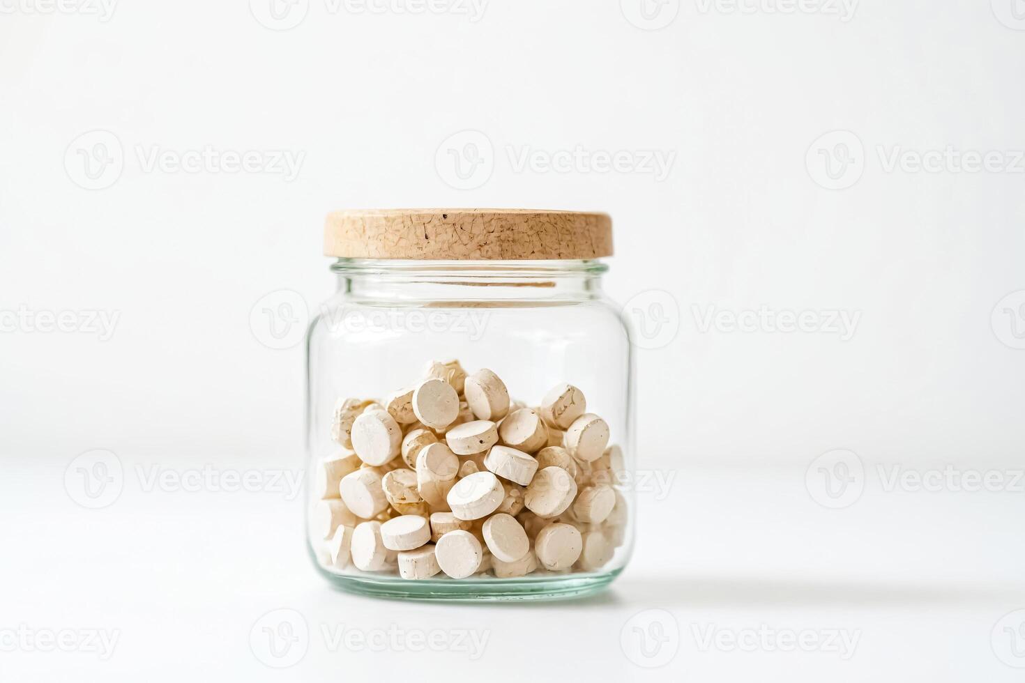 White pills in a glass jar with a cork lid photo