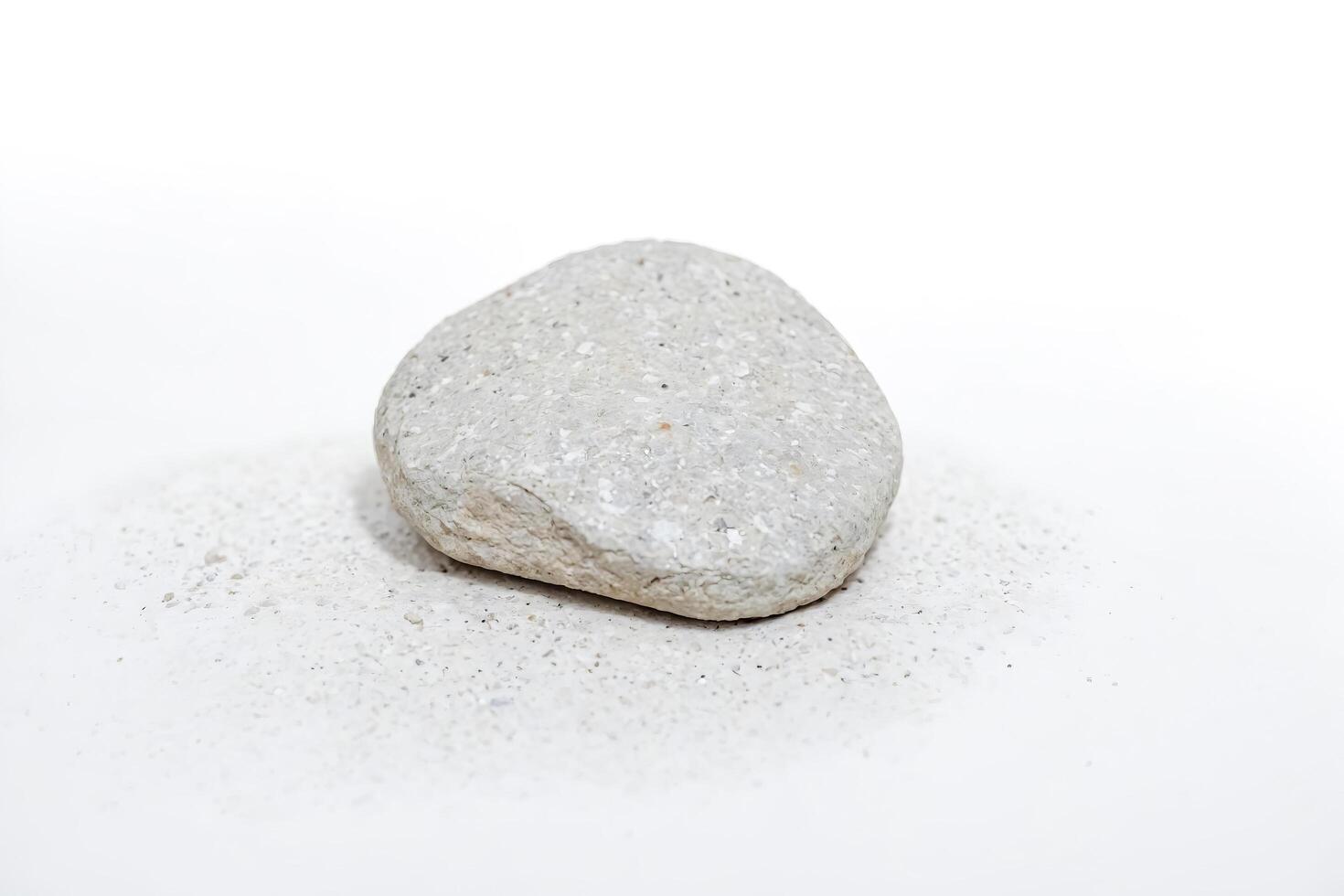 Single white rock on a white surface with tiny white pebbles photo