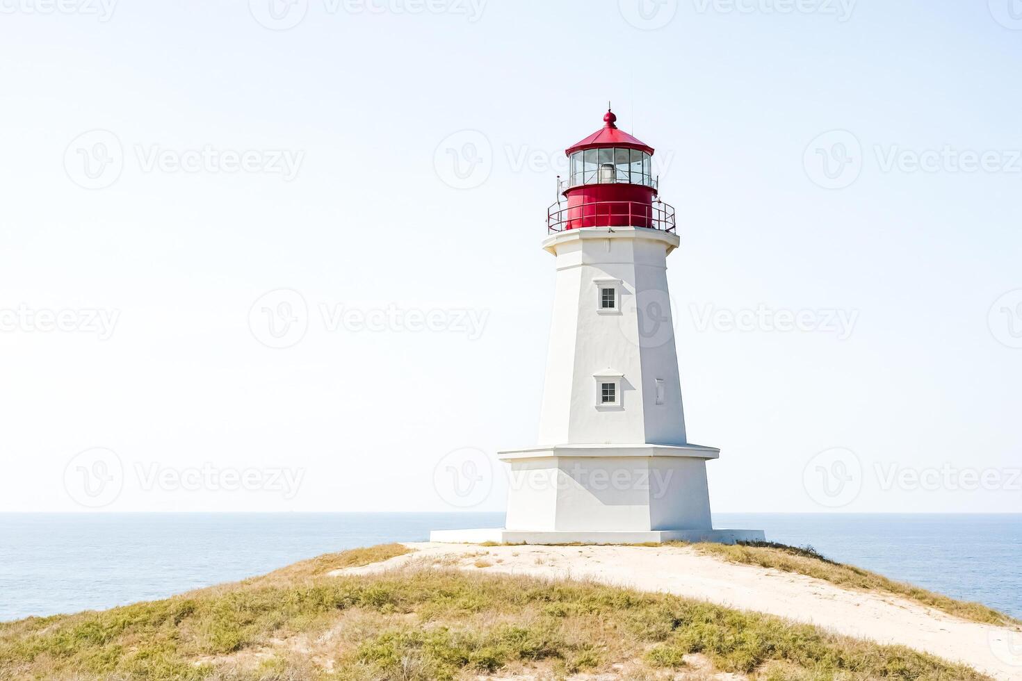 White Lighthouse on a Cliff overlooking the ocean photo