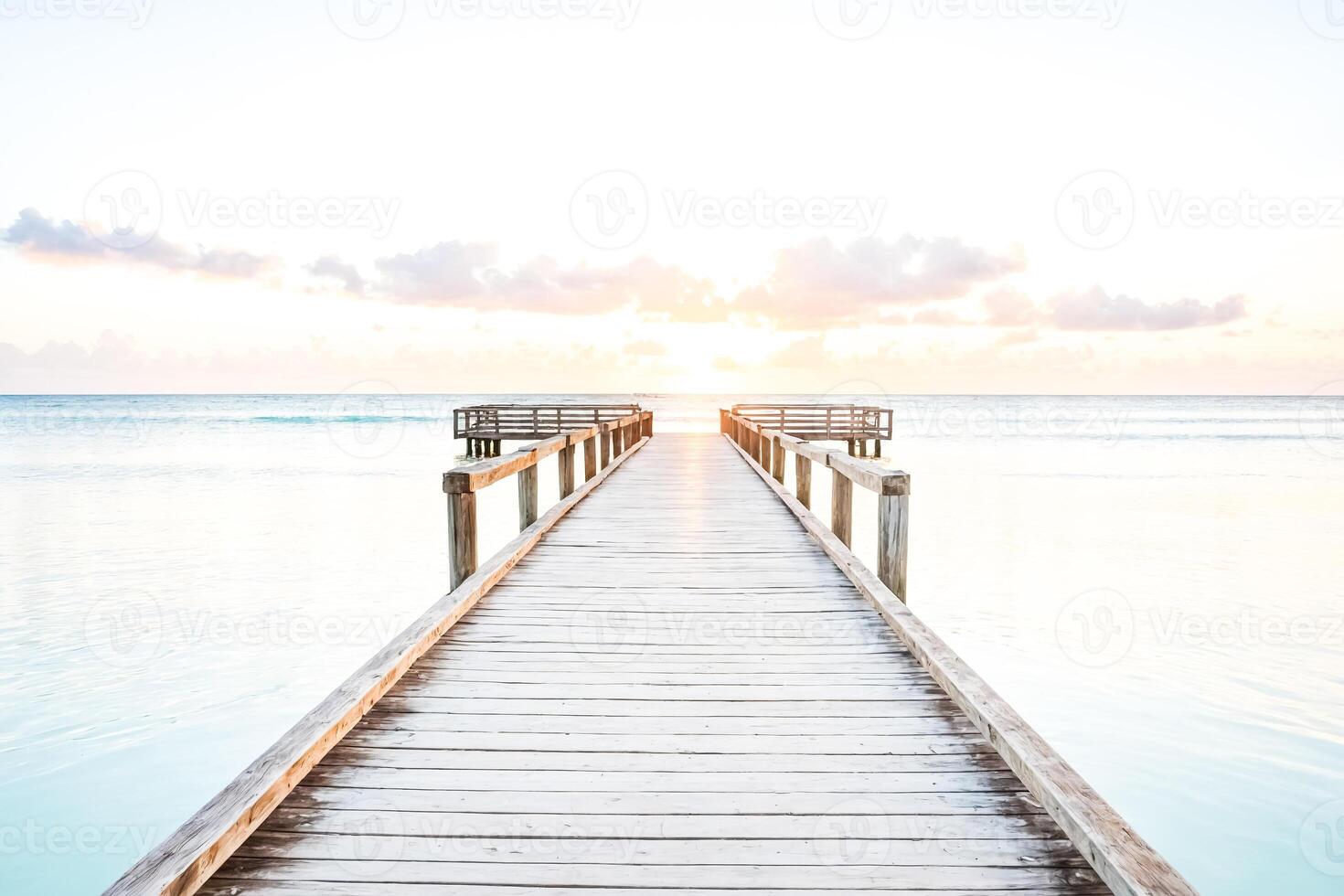 Wooden pier extending into the ocean at sunset photo