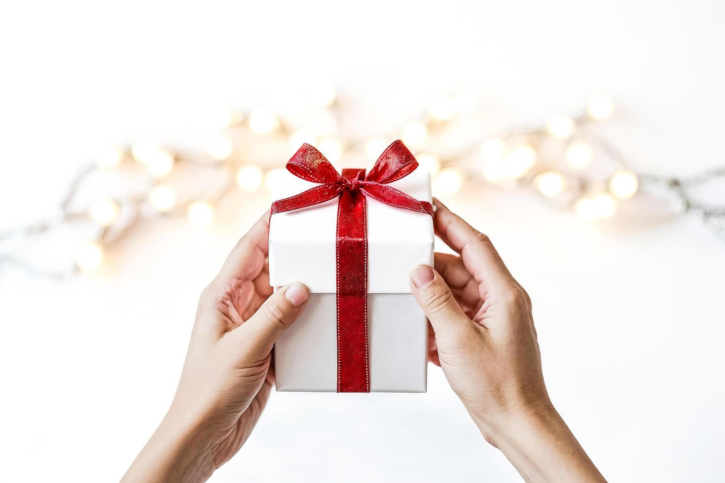 Close-up of hands holding a gift box with red ribbon photo