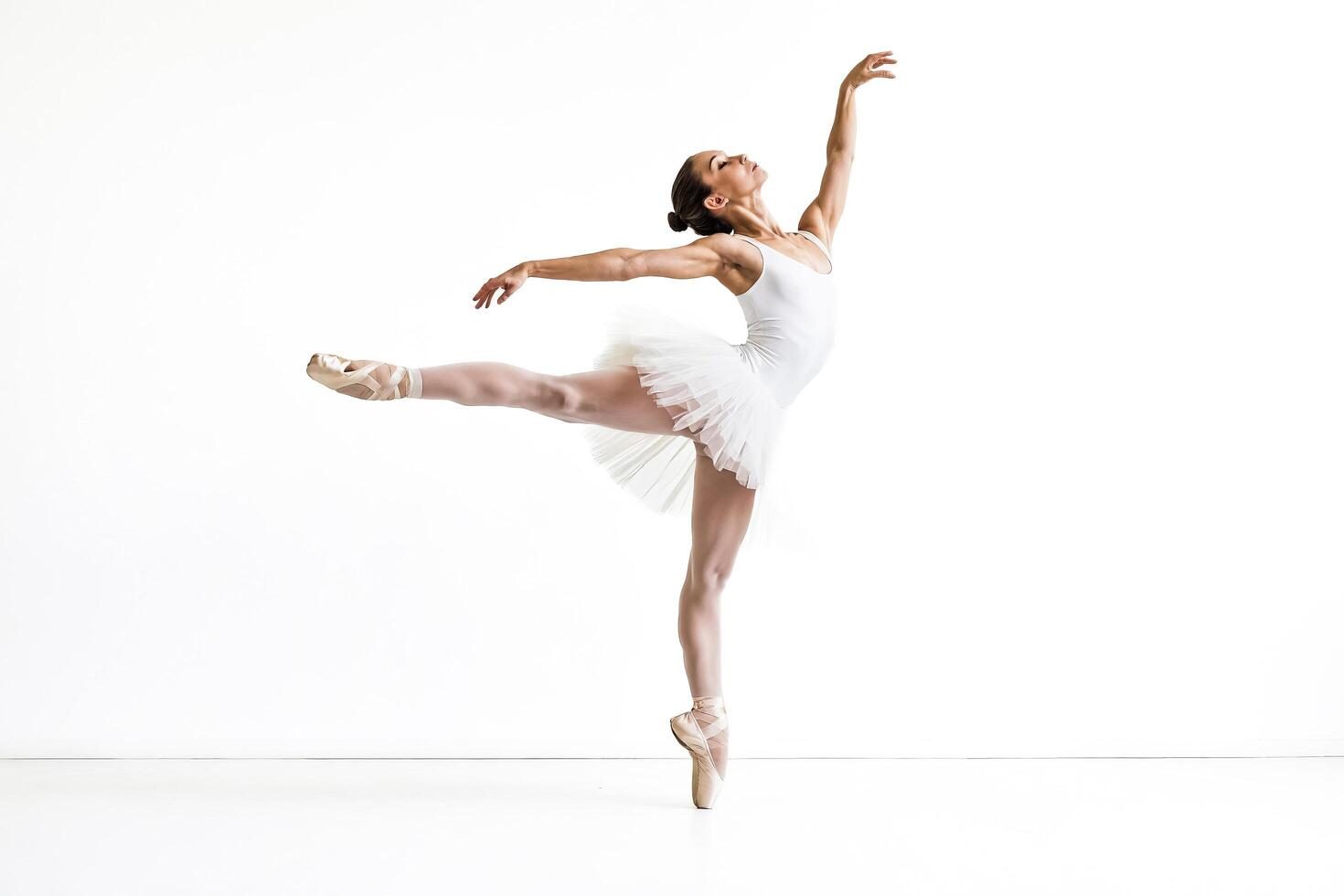 Ballerina in white tutu and pointe shoes, performing a graceful pose against a white background photo