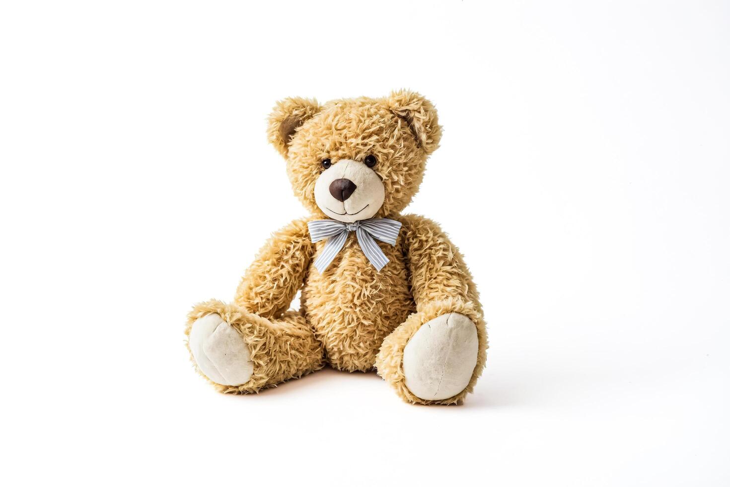 Plush teddy bear with blue bow sitting on a white background photo