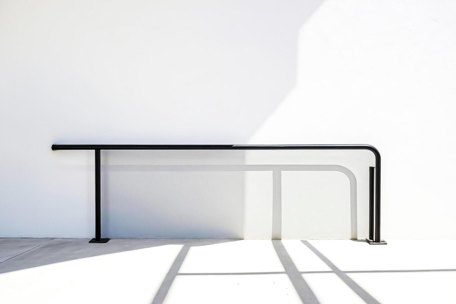 Minimalist Black Railing Against White Wall with Light and Shadow photo