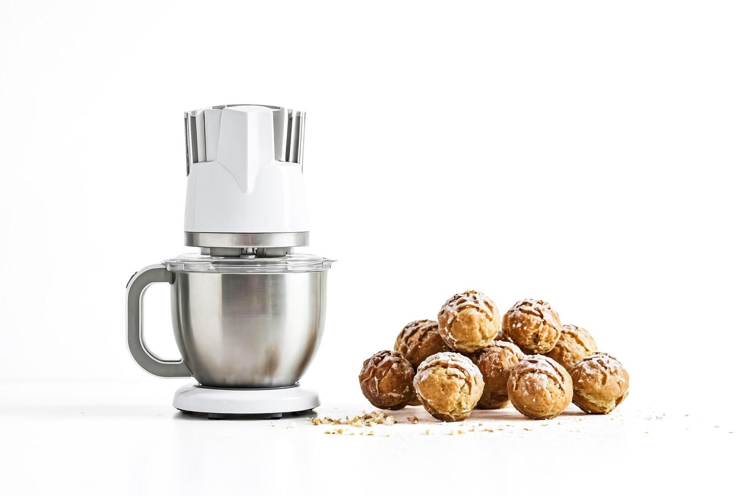 White stand mixer with a bowl full of dough next to a pile of eclairs photo