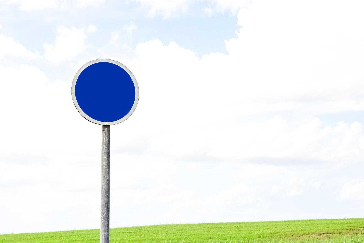 Blue Road Sign With White Arrow Pointing Up In A Grass Field photo