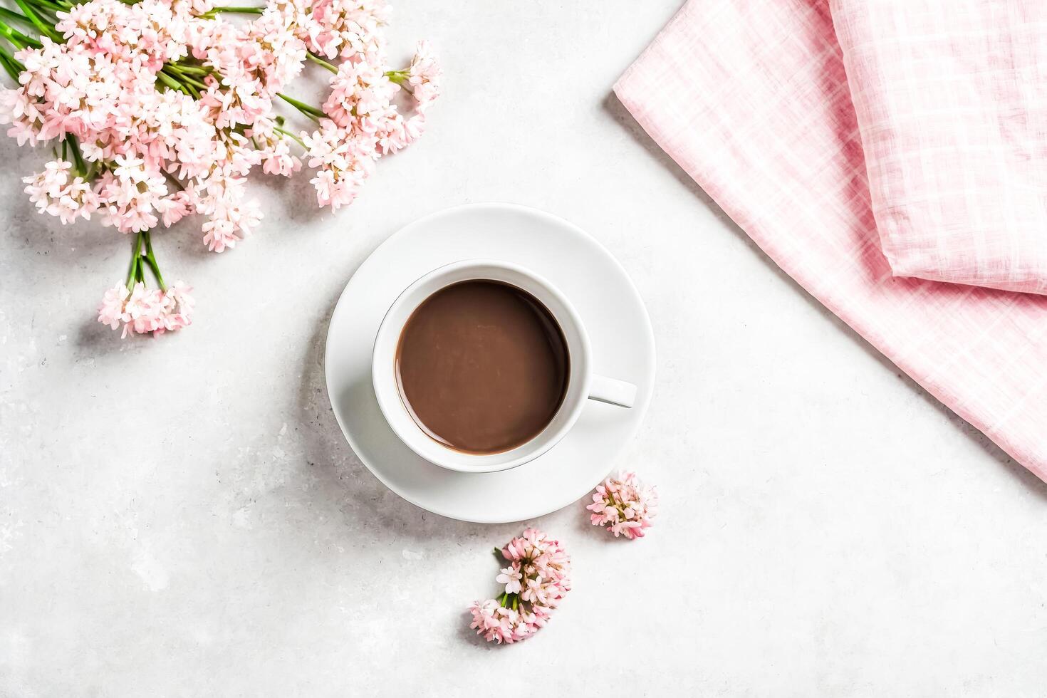 Flat lay composition with a cup of coffee and pink flowers photo