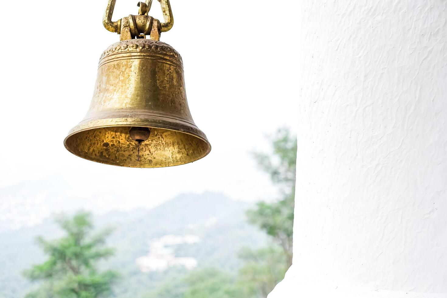 Golden Bell Hanging Against a White Wall photo