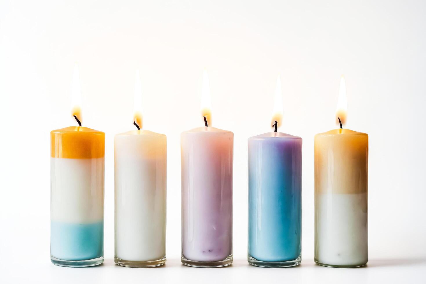 Row of five burning candles with different color wax photo