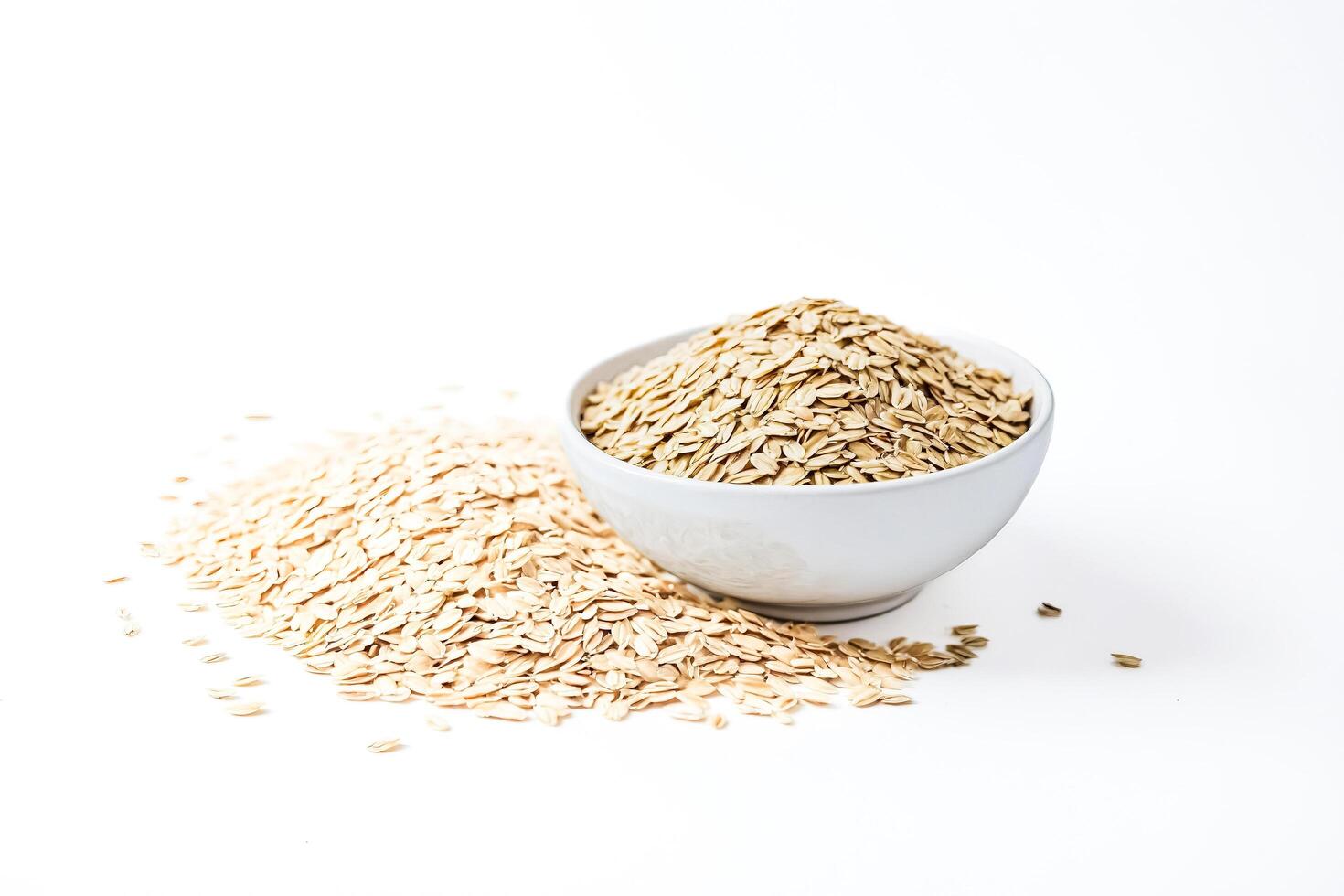 Bowl of Oats with Spilled Grain on White Background photo