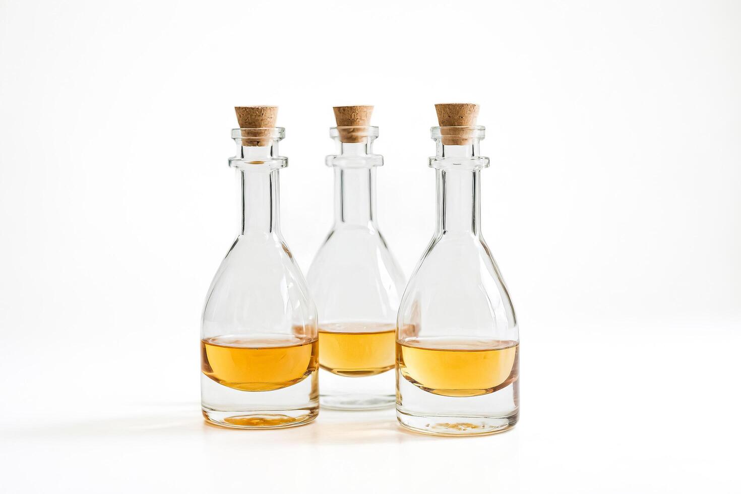 Three Glass Bottles with Cork Stoppers and Golden Liquid photo