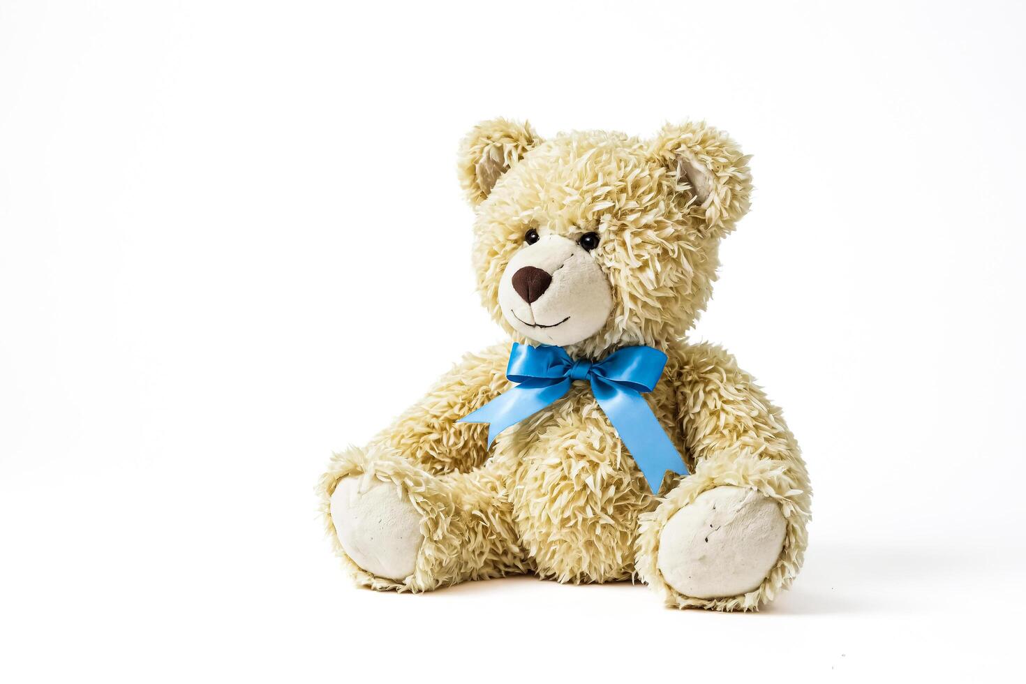 Plush Teddy Bear with Blue Bow Sitting on White Background photo