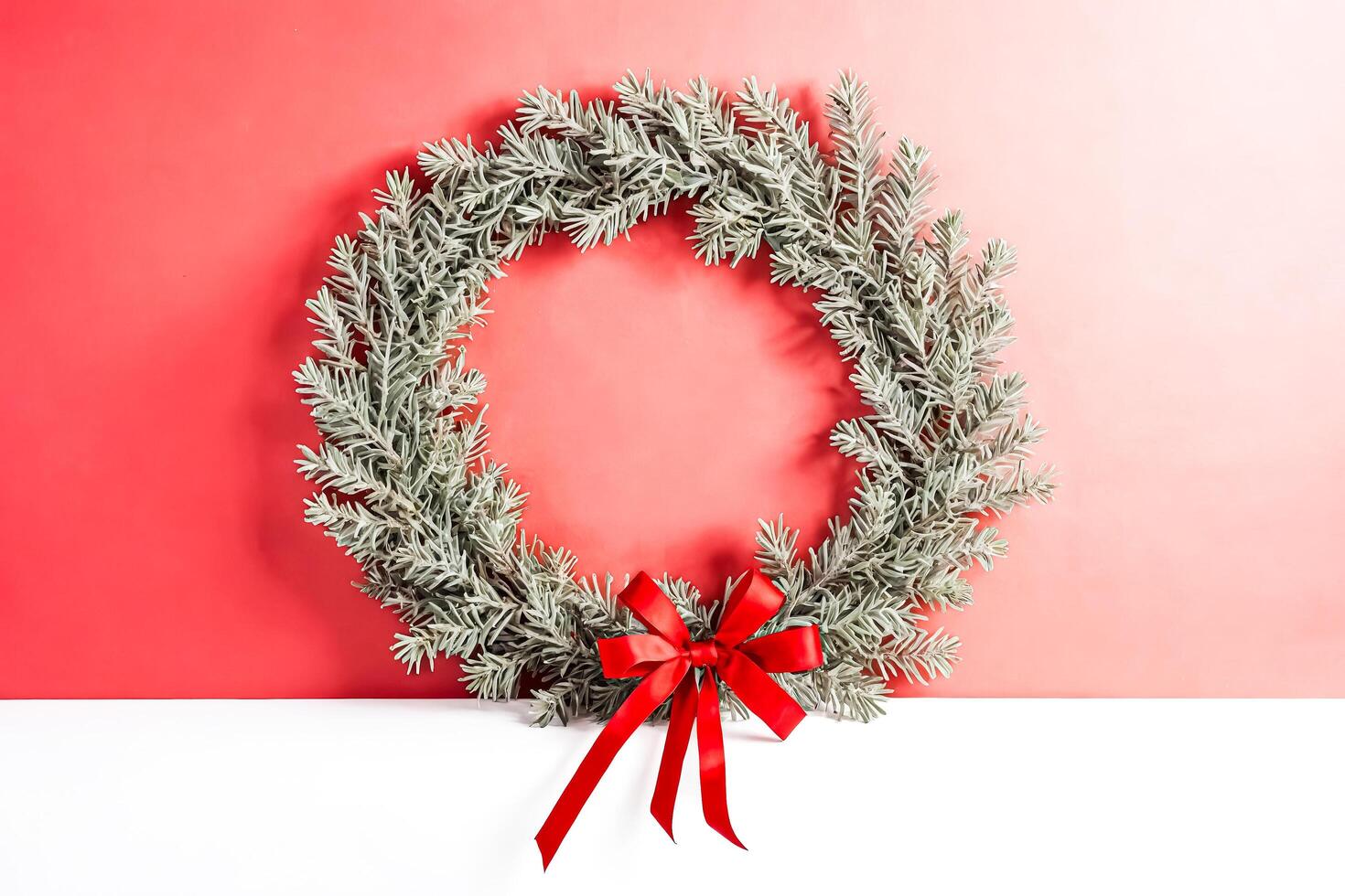 Minimalist Christmas Wreath with Red Bow on Pink and White Background photo