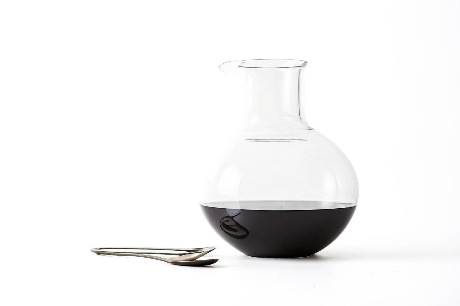 Glass Decanter with Red Wine and Two Spoons on White Background photo