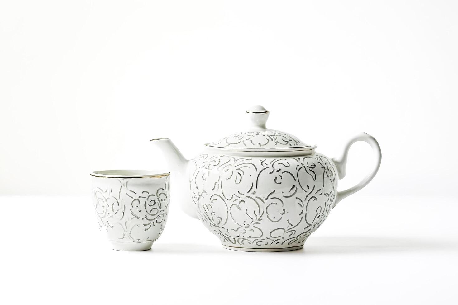 White Teapot and Cup with Floral Design on White Background photo