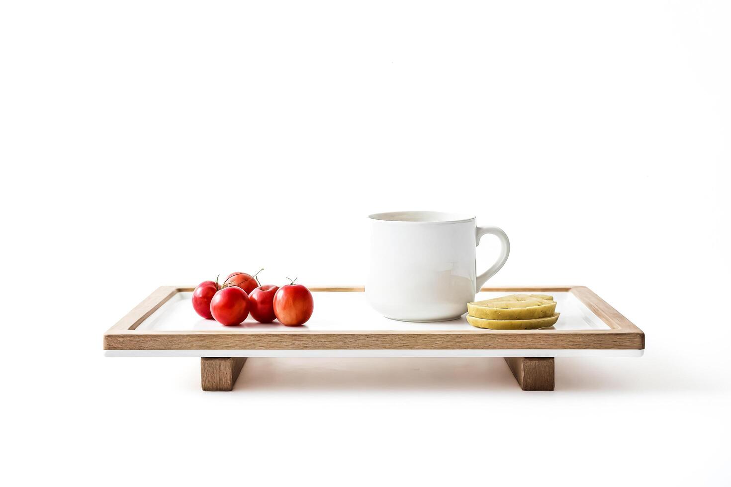 White Mug with Red Tomatoes and Green Apple Slices on a White and Wooden Serving Tray photo