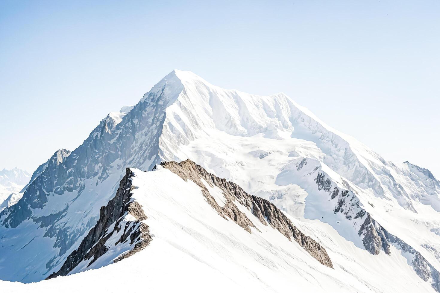 Majestic Snow-Capped Mountain Peak Against a Clear Blue Sky photo