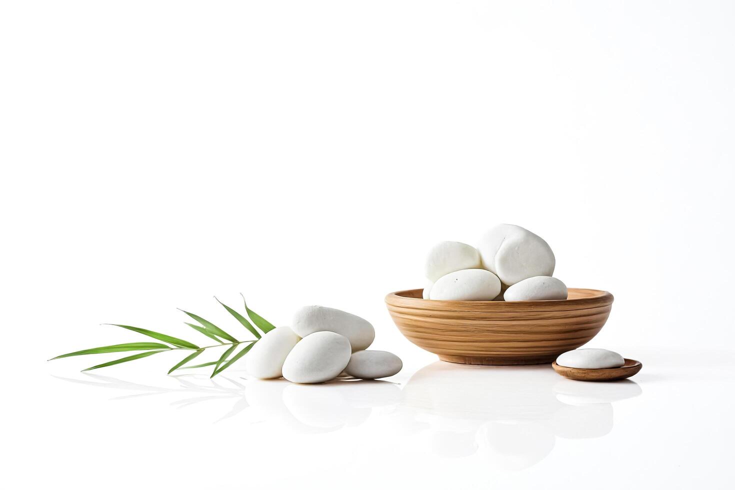 White Stones and Green Leaves in a Wooden Bowl on White Background photo