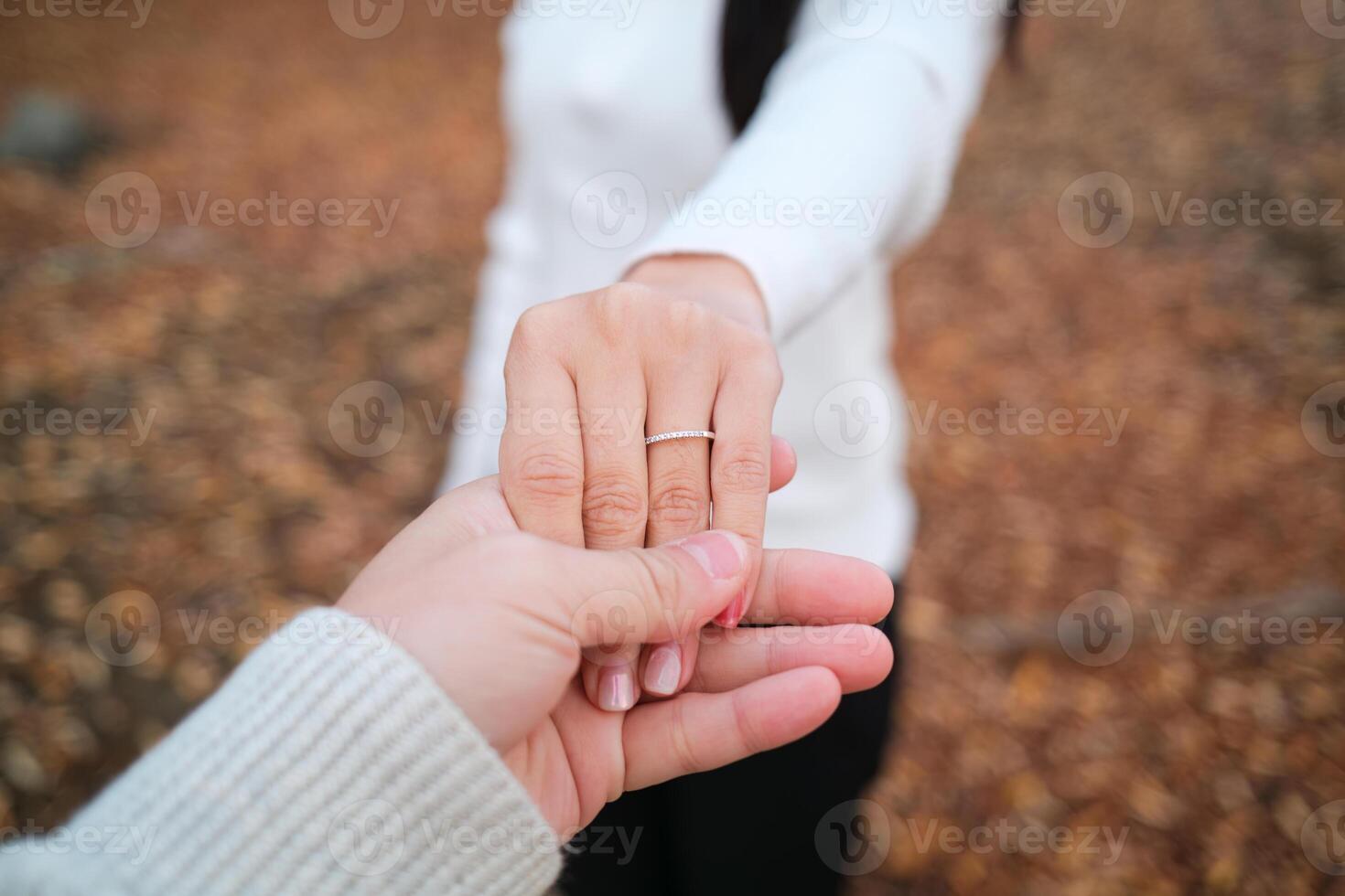 Couple holding hands with a engagement ring on the bride finger photo