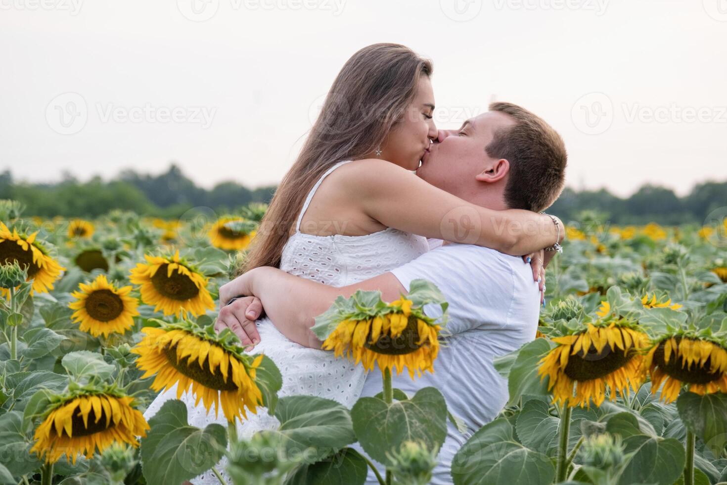 Cheerful couple in sunflowers in field at sunset photo