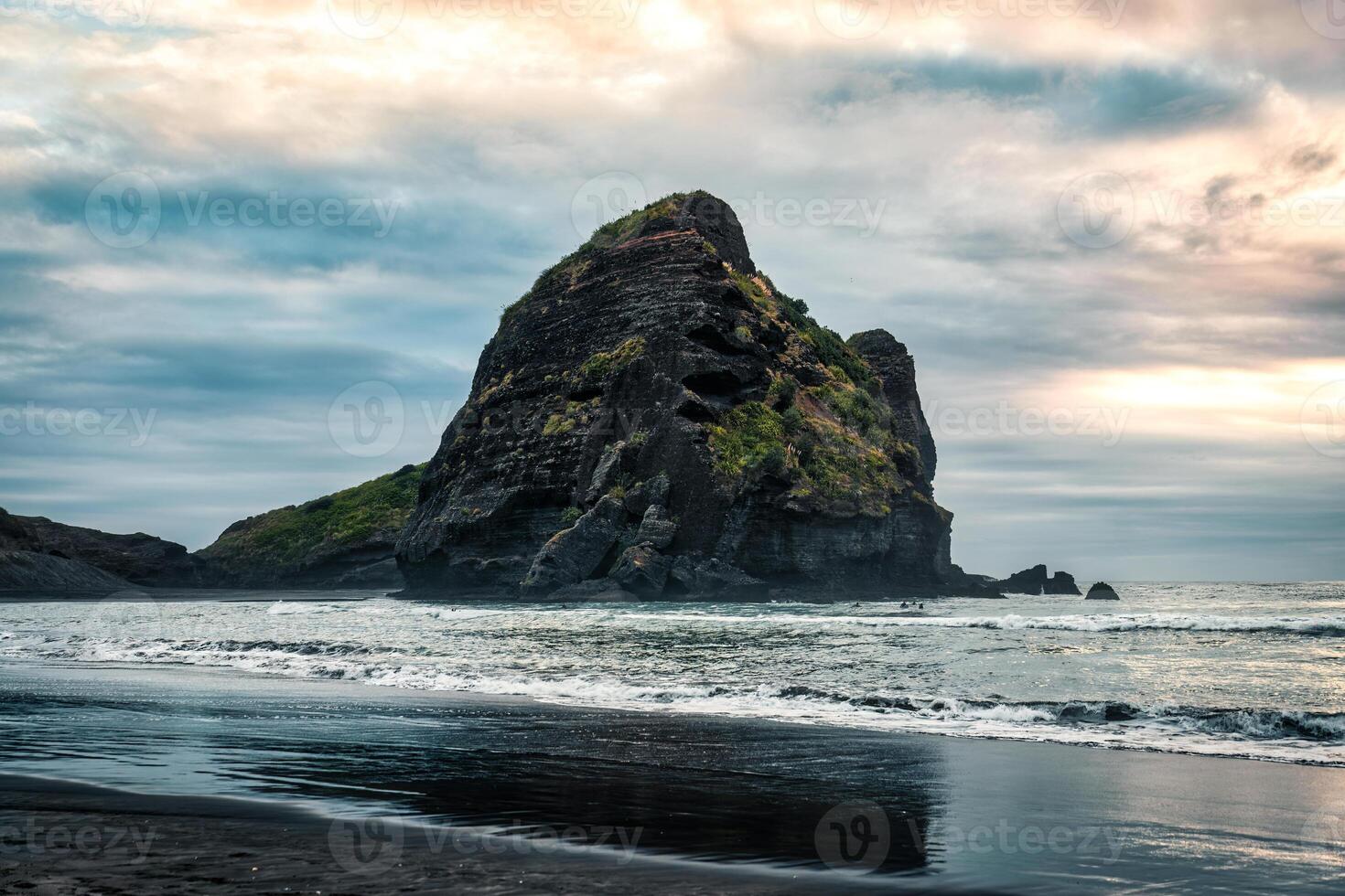 Rocky mountain on Piha beach in the evening at West coast of Auckland photo