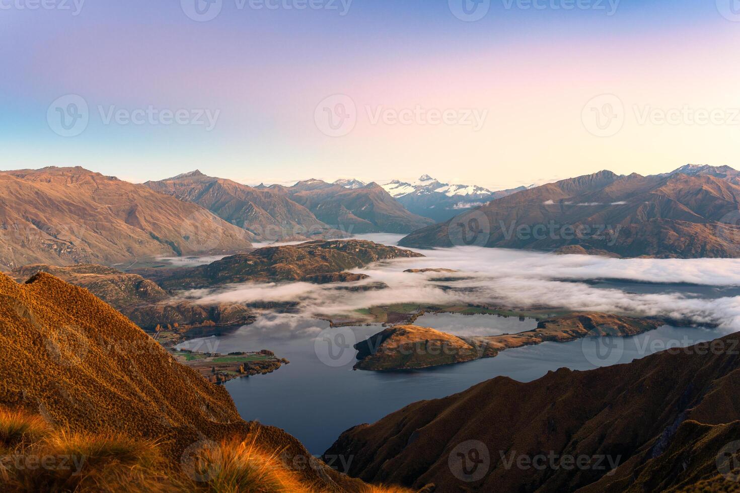 Sunrise shining over summit of Roys Peak and foggy mountain over Lake Wanaka in autumn at New Zealand photo