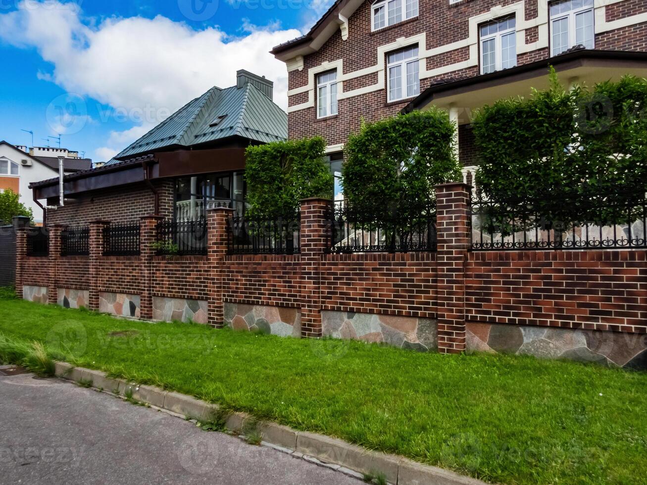 combined brick and wrought iron fence with brick pillars on a strip foundation near a country house photo