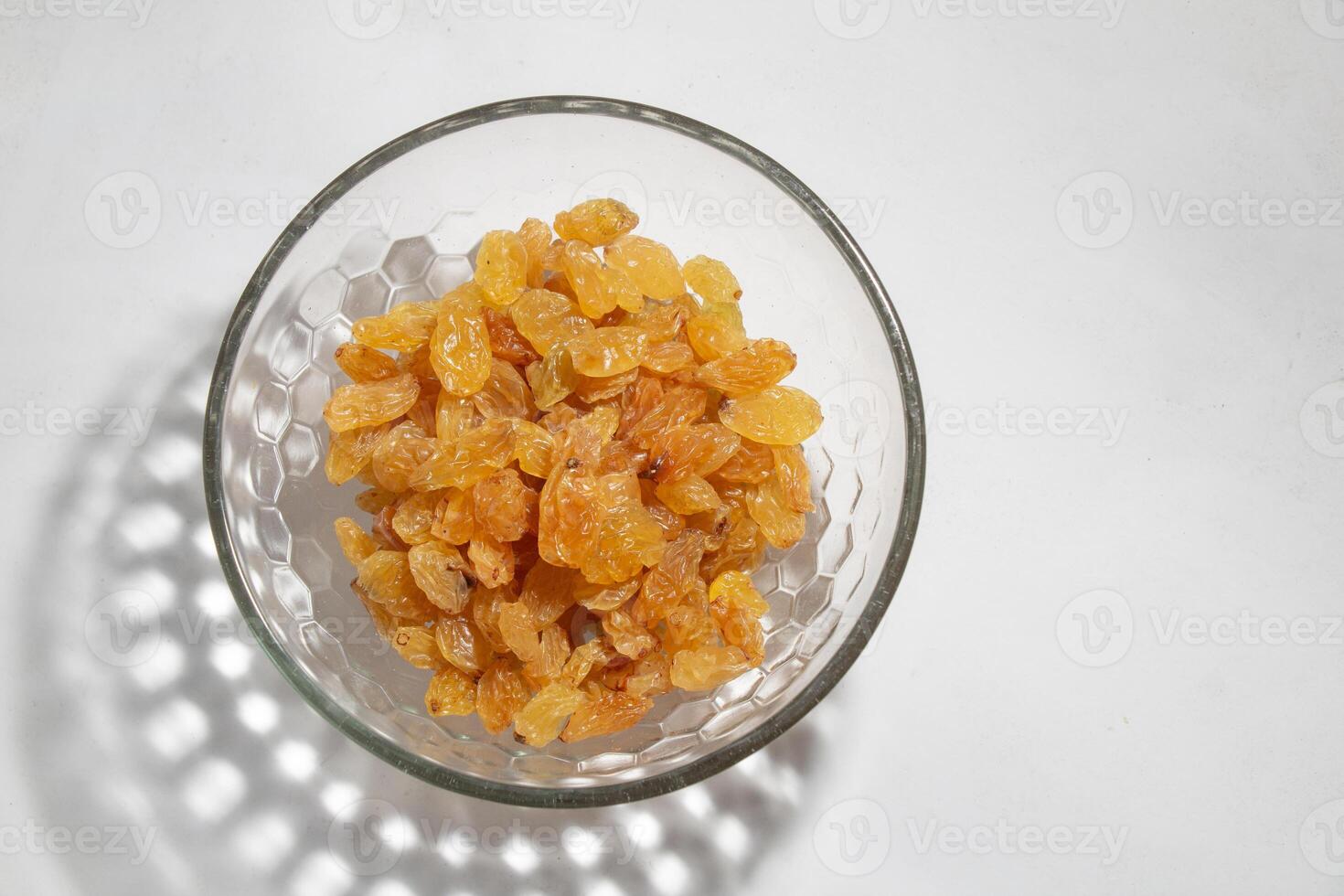 top view Yellow raisins in an open glass bowl, isolated on white, with bowl shadow, negative space photo