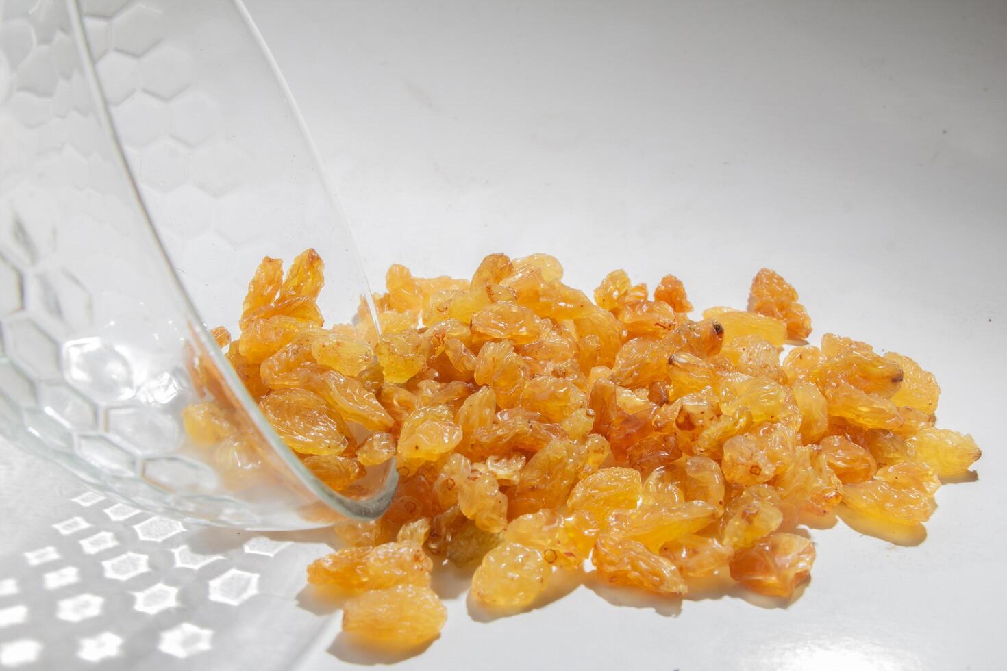 Front bottom view Yellow raisins in open glass bowl, isolated white, negative space photo
