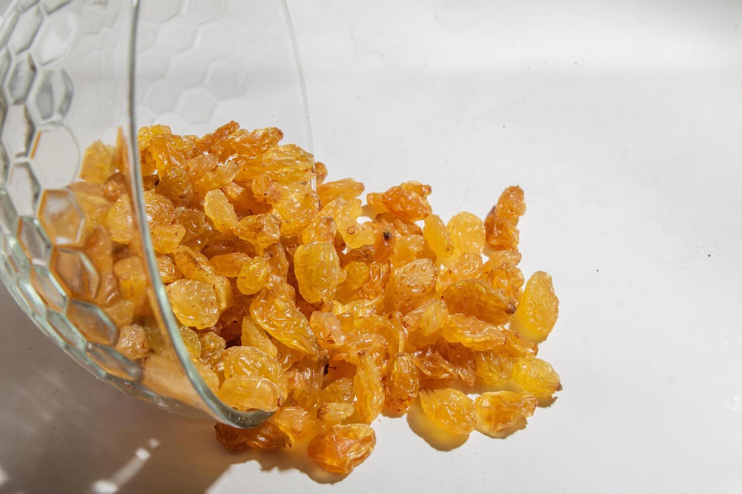 Yellow raisins in a glass bowl, isolated on white, negative space photo