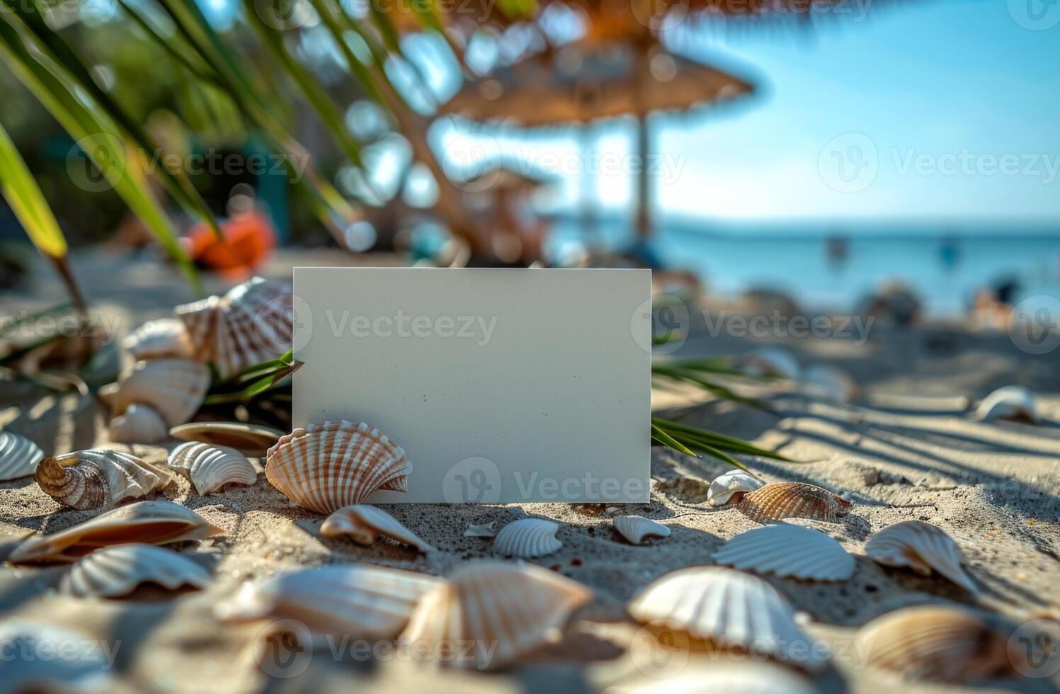 Blank card on a sandy beach with seashells, palm leaves, and ocean in the background, tropical vibe photo