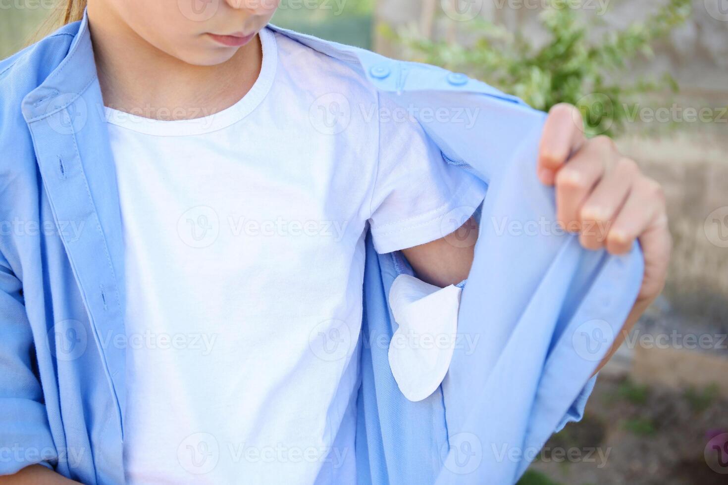 The teenager shows a strip of sweat attached to the armpits of shirt. photo