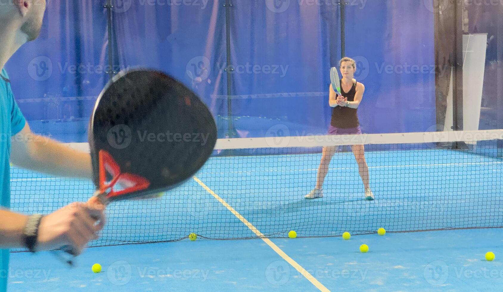 Empowering padel tennis training as a coach skillfully instructs a young woman on the court, fostering skill development and a positive learning environment photo