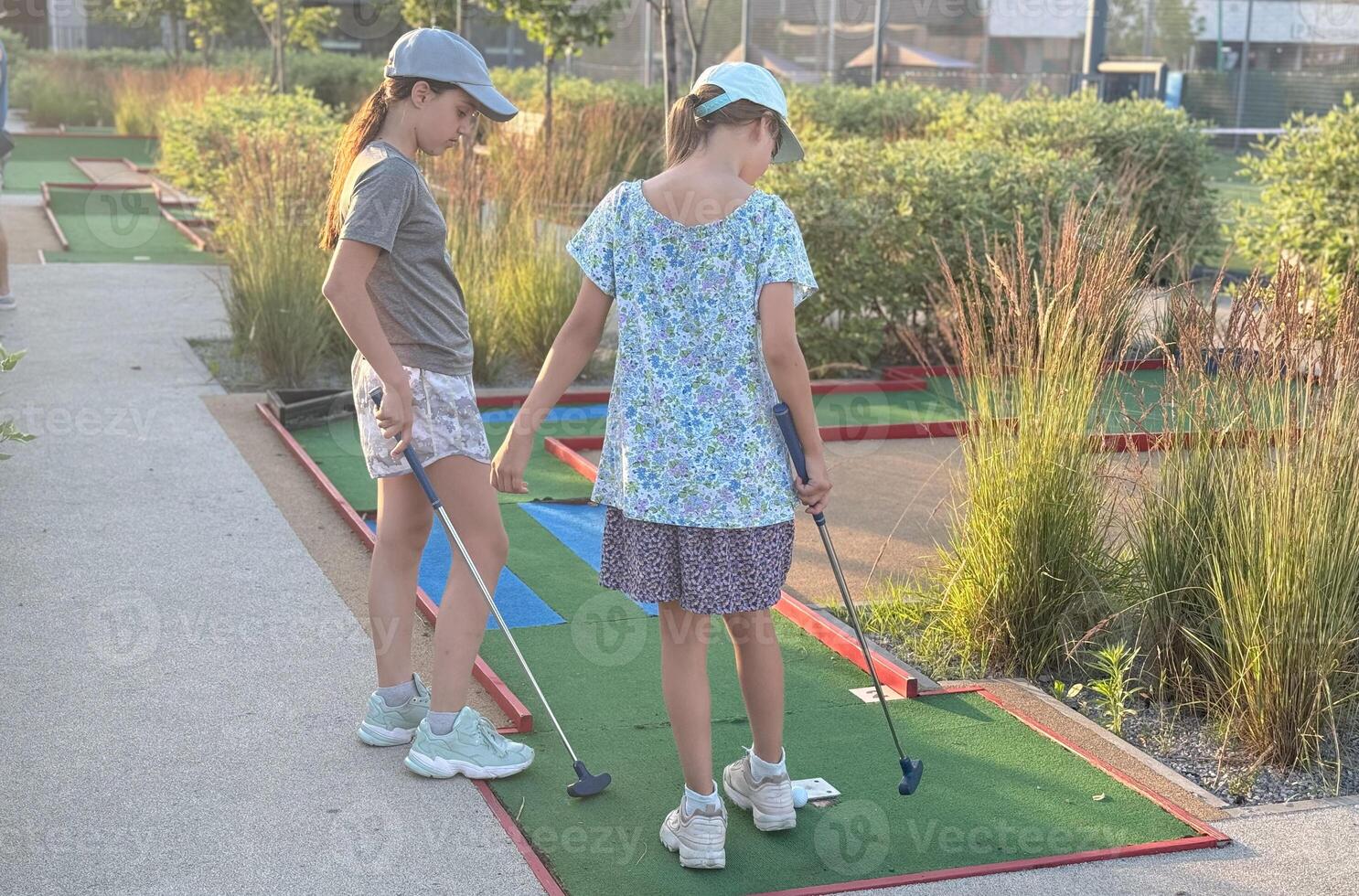 teenage girls playing mini golf in summer photo