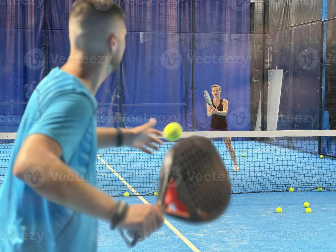 Empowering padel tennis training as a coach skillfully instructs a young woman on the court, fostering skill development and a positive learning environment photo