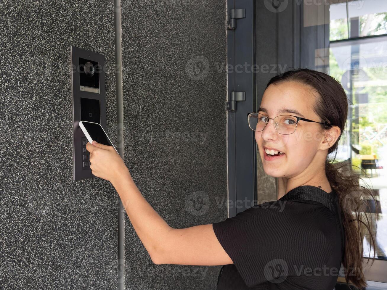 teenage girl using phone scan to digital door lock security systems at home. photo