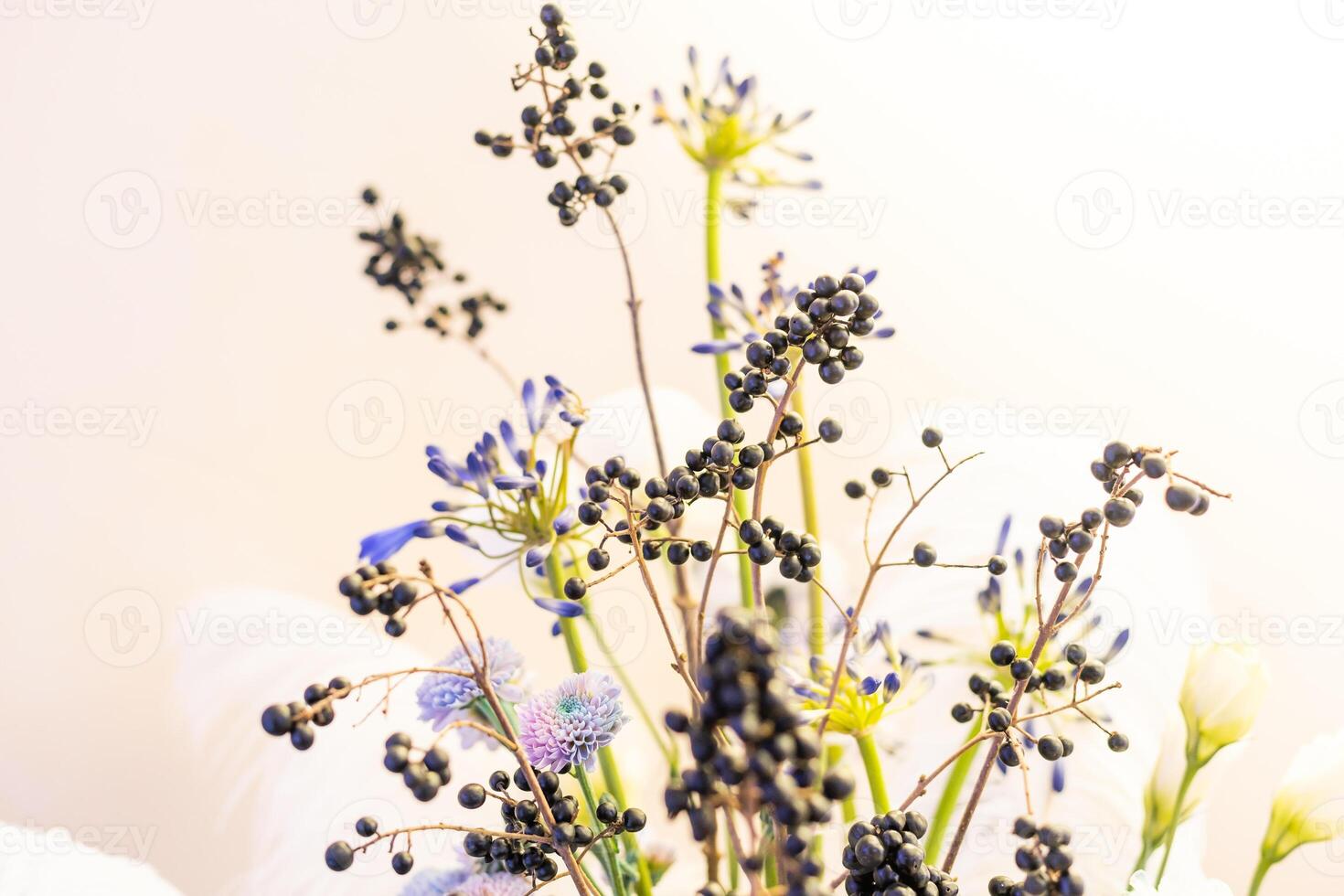 Beautiful flower composition with autumn flowers and berries. Autumn bouquet in vintage vase on a white wall background photo