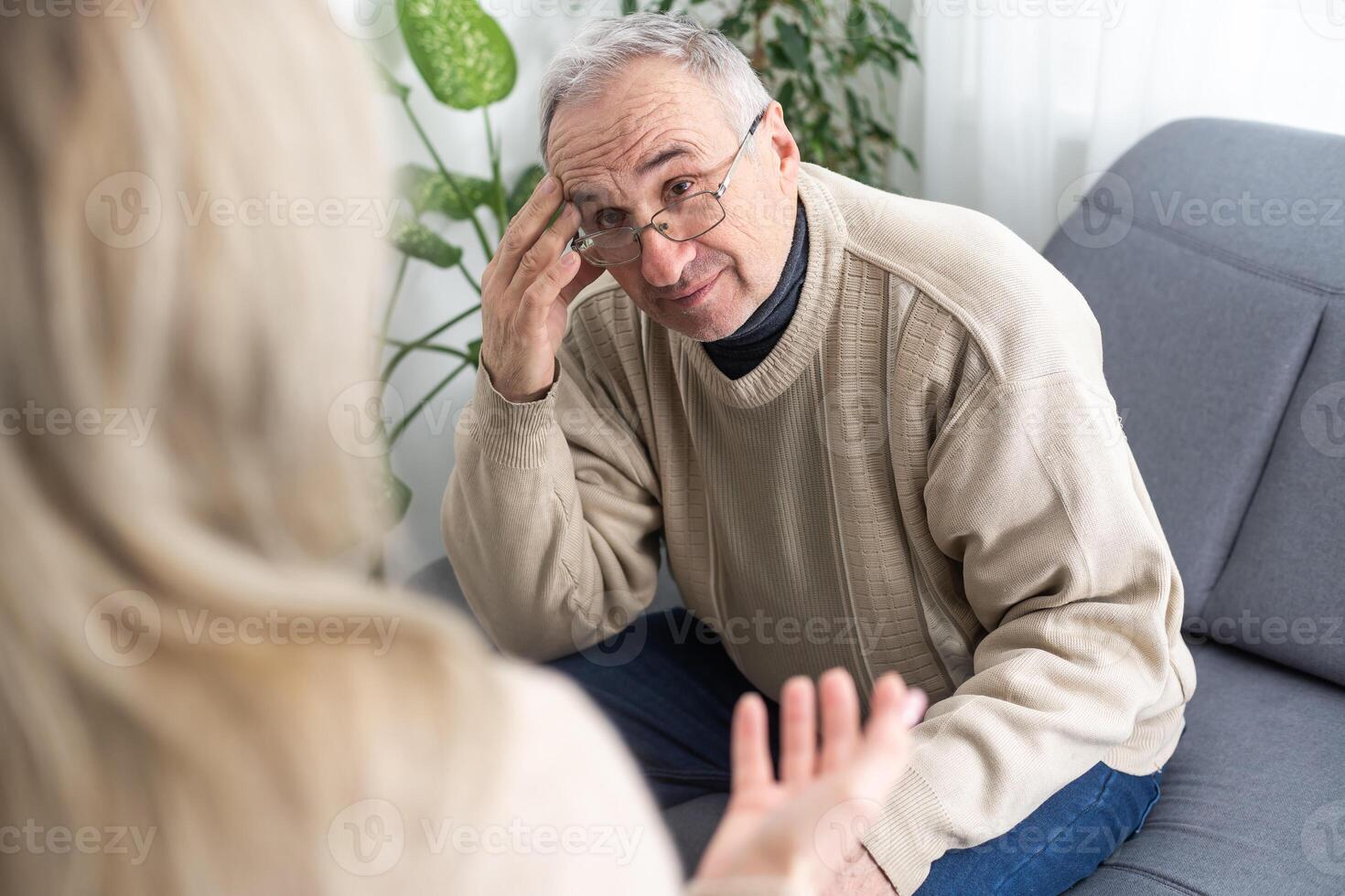 Mature man at a session with a psychologist. The doctor listens and writes. Help with depression, psychiatric diagnosis. photo