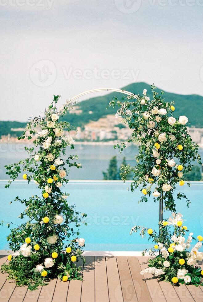 Wedding arch stands on the shore of the pool photo