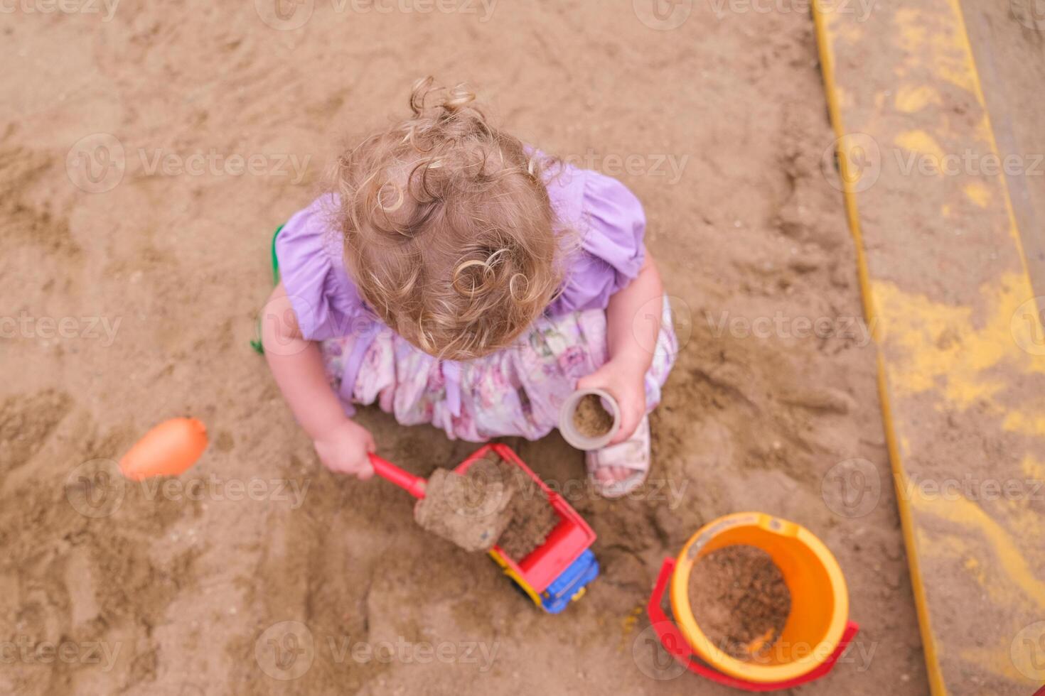 Child playing in the sandbox in the playground in the courtyard of a house photo