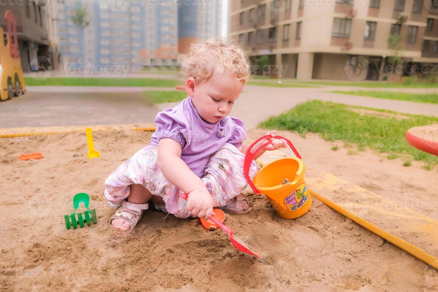 Child playing in the sandbox in the playground in the courtyard of a house photo