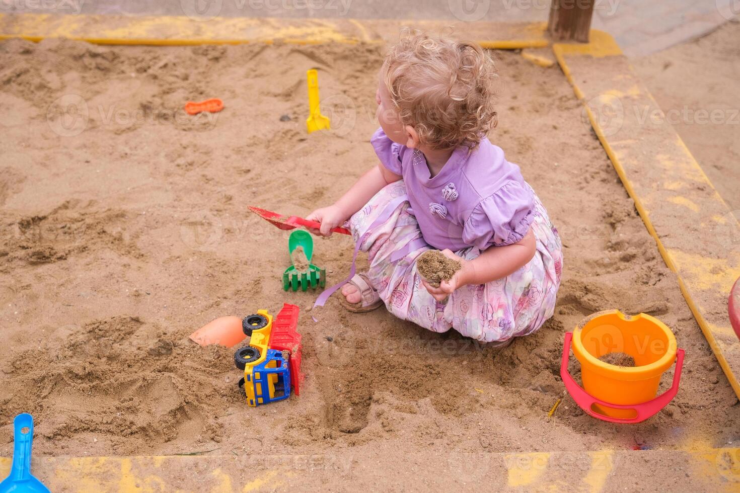Child playing in the sandbox in the playground in the courtyard of a house photo