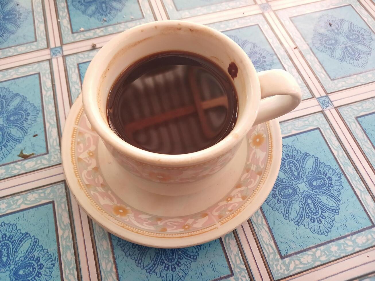 Cup of coffee isolated on blue checkered tablecloth background photo