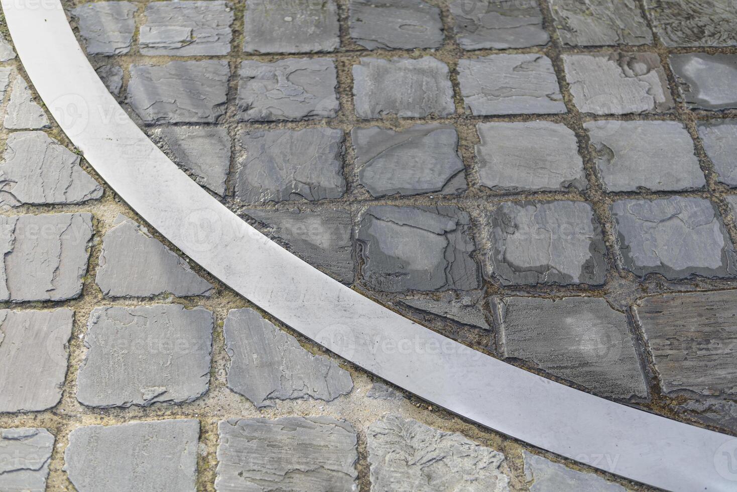 Metal arc insert in a stone pavement. Fragment circle. Different color of stone photo