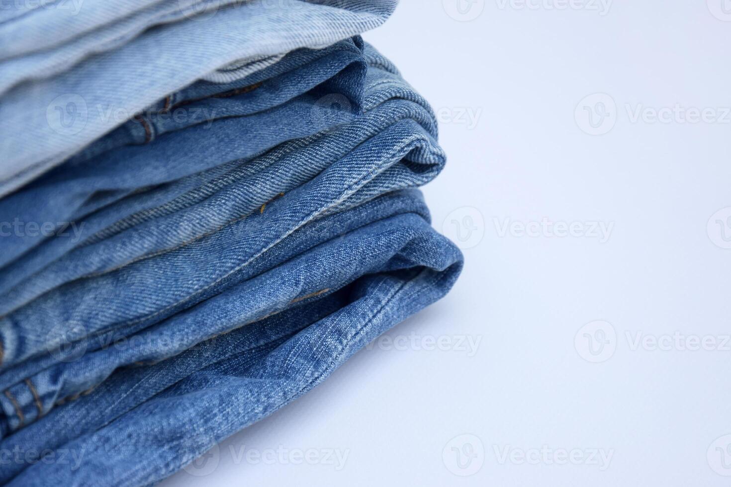 Lots of jeans pants in a stack. Denim background. photo