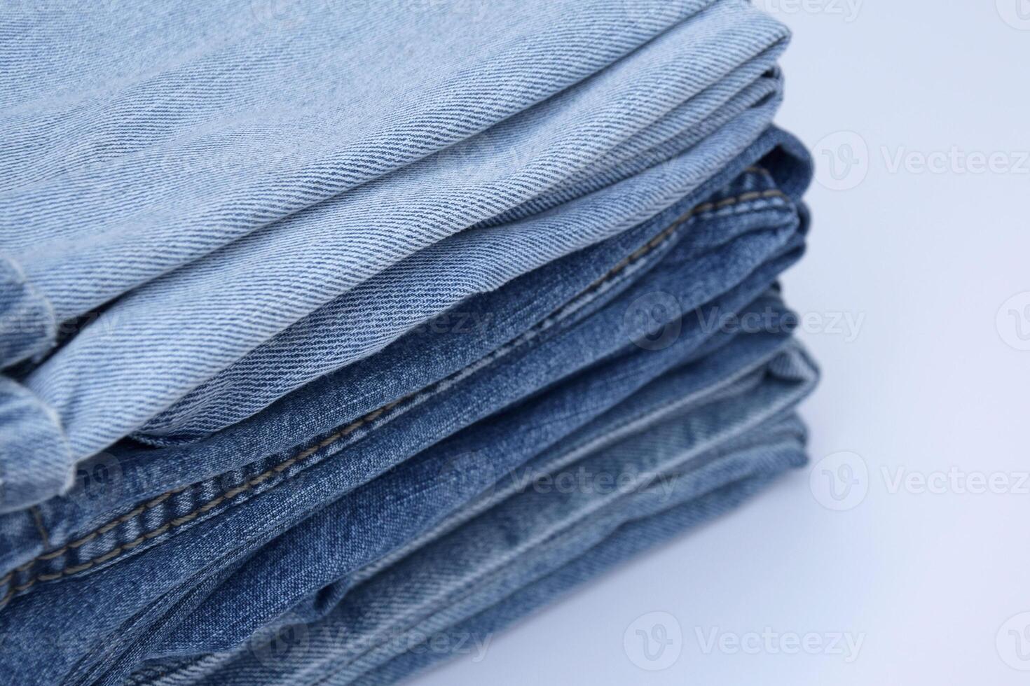 Lots of jeans pants in a stack. Denim background. photo