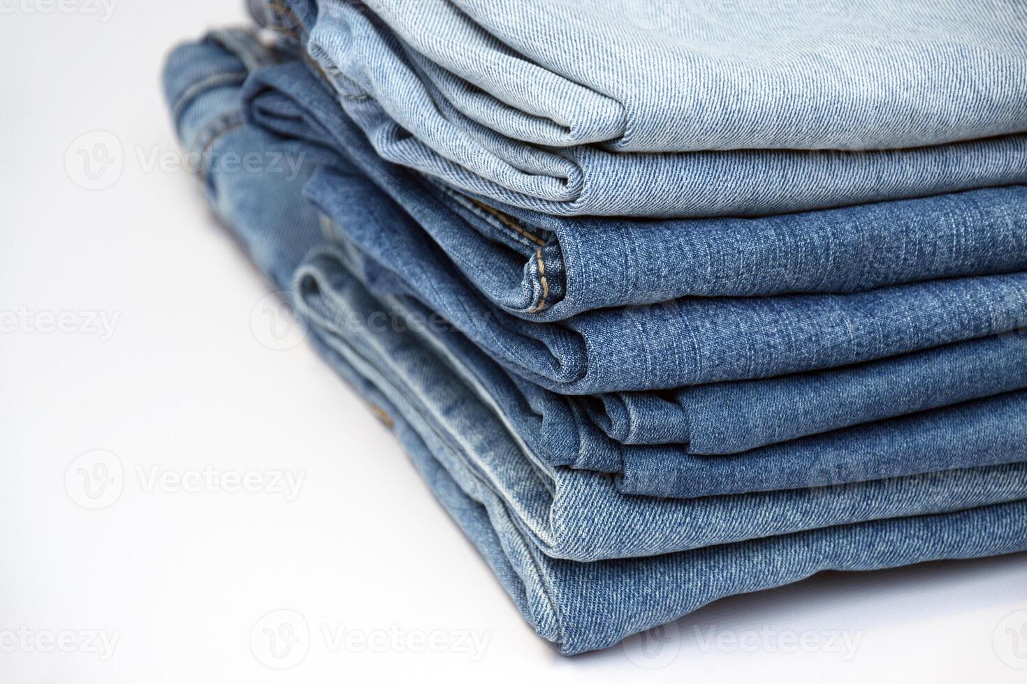 Lots of jeans pants in a stack. Denim background. photo